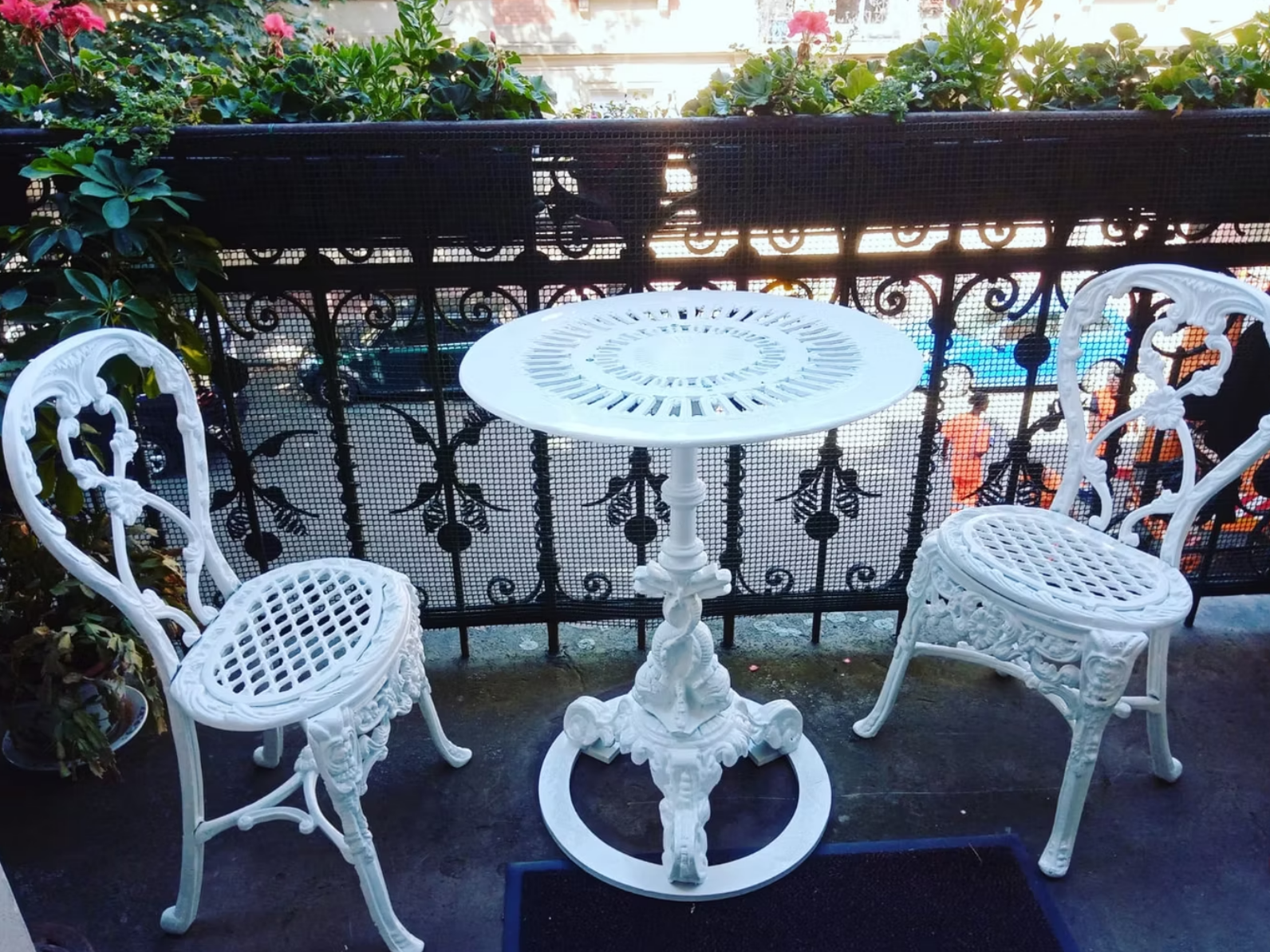 Zwei weiße Stühle und ein weißer Tisch auf einem Balkon