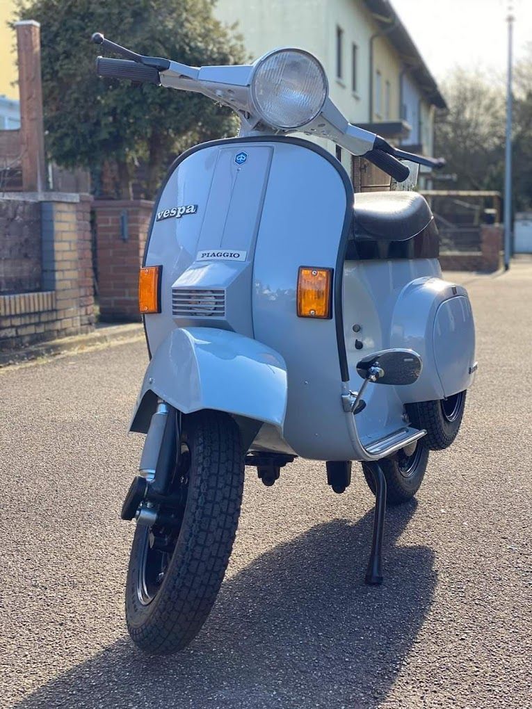 Ein Motorroller ist am Straßenrand vor einem Gebäude geparkt.