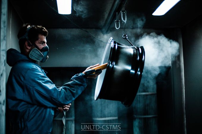 Ein Mann mit einer Maske sprüht Pulver auf einen Metallgegenstand.