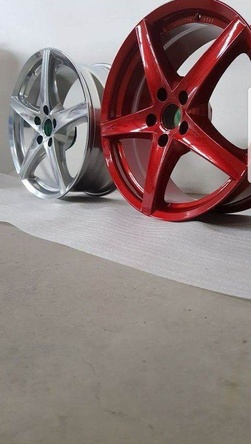 Auf einem Tisch stehen zwei Felgen nebeneinander. Eines ist silbern und das andere ist rot.