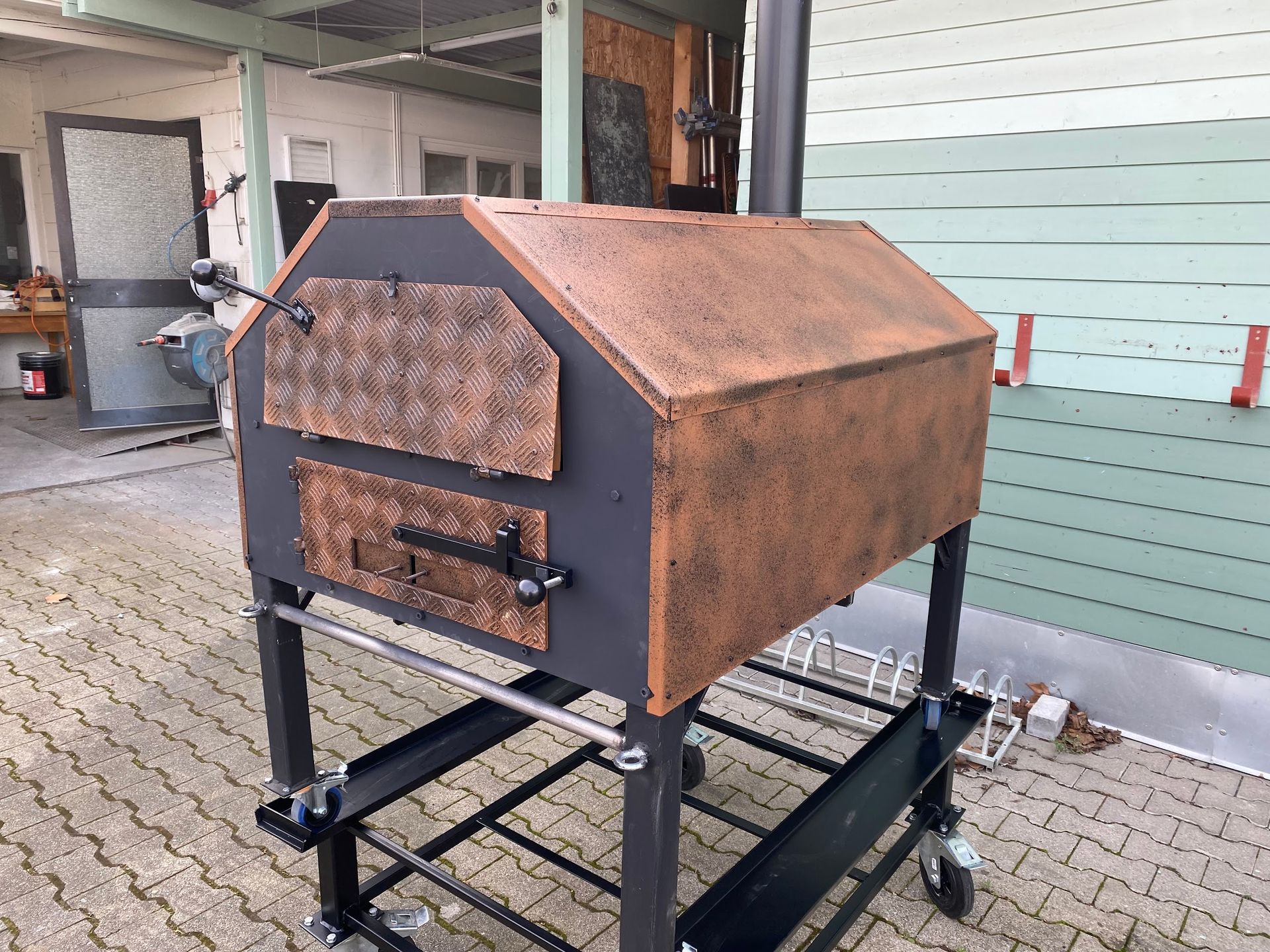 Ein großer Kupferofen steht auf einem Wagen vor einem Gebäude