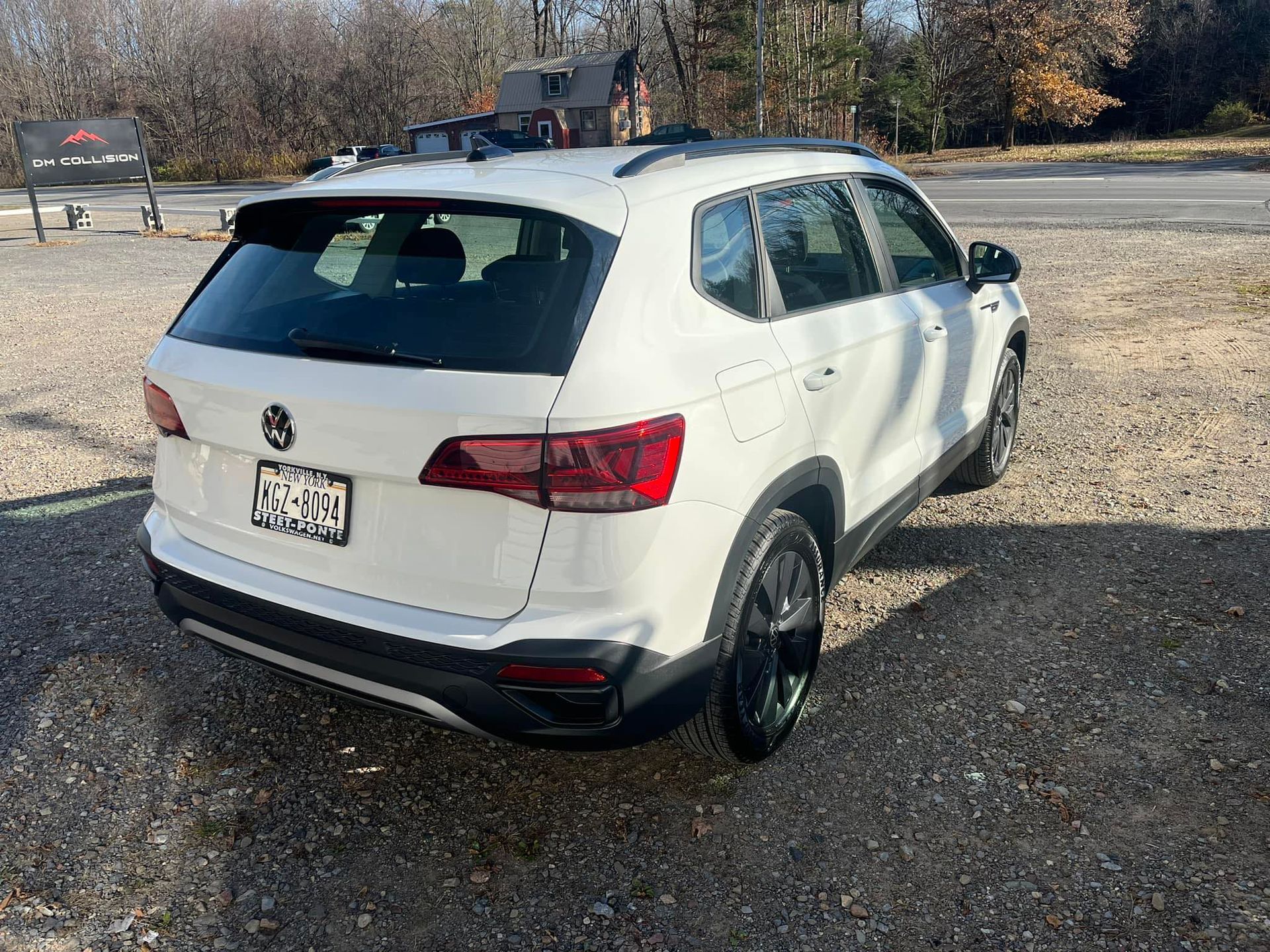 A white Volkswagen Tiguan SUV parked on a gravel lot under a clear, sunny sky.