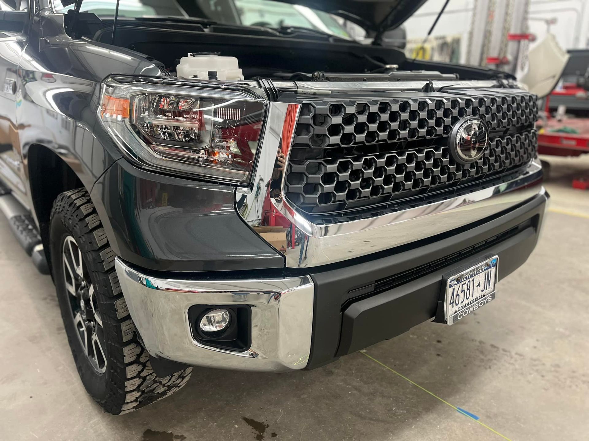Front three-quarter view of a dark gray Toyota Tundra pickup truck with a chrome grille and bumper in a garage.