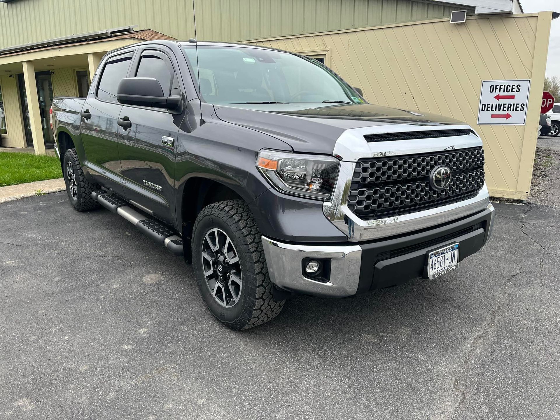 A dark gray Toyota Tundra pickup truck parked on an asphalt lot in front of a building.