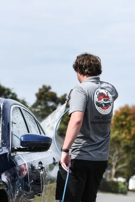 A man is washing a car with a hose.