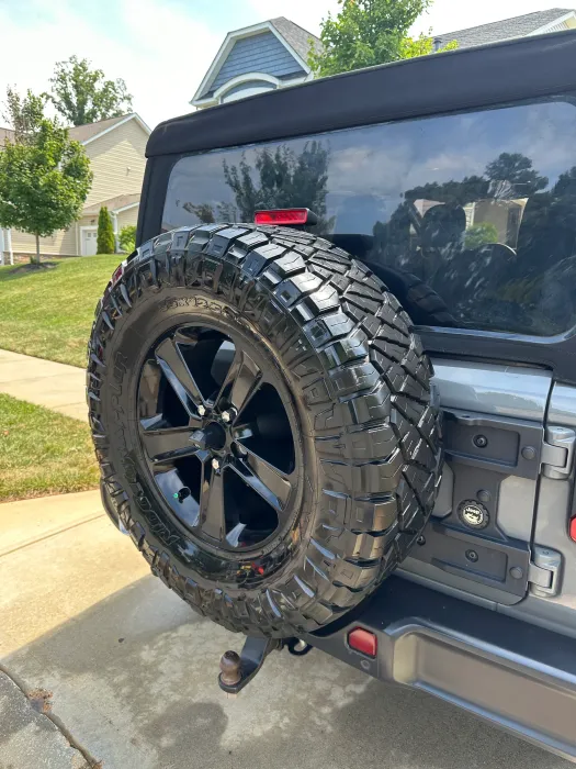 A jeep with a spare tire attached to the back of it is parked on the side of the road.