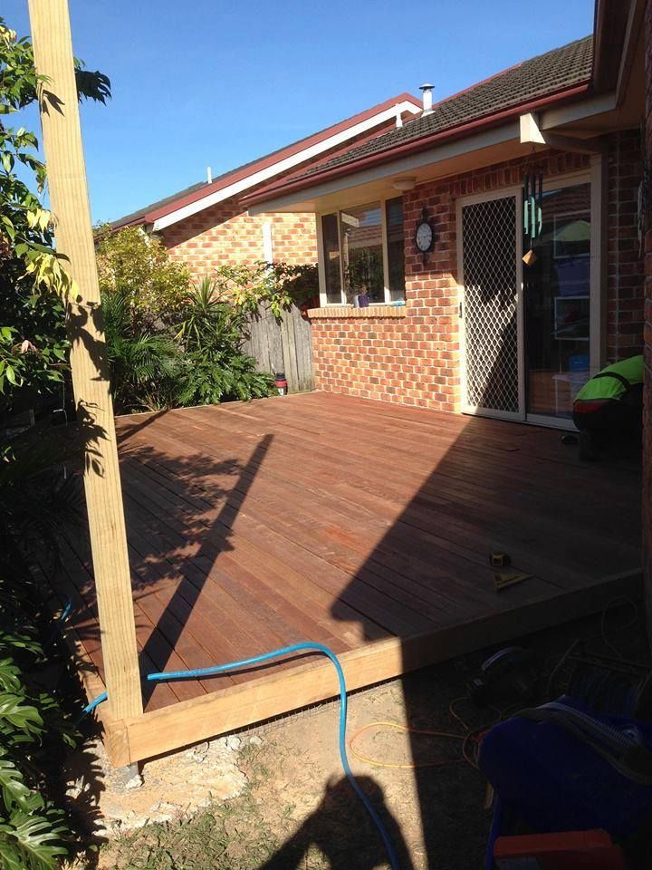 A Wooden Deck is Being Built in Front of a Brick House — Mark Cannon Carpentry & Maintenance in Moonee Beach, NSW