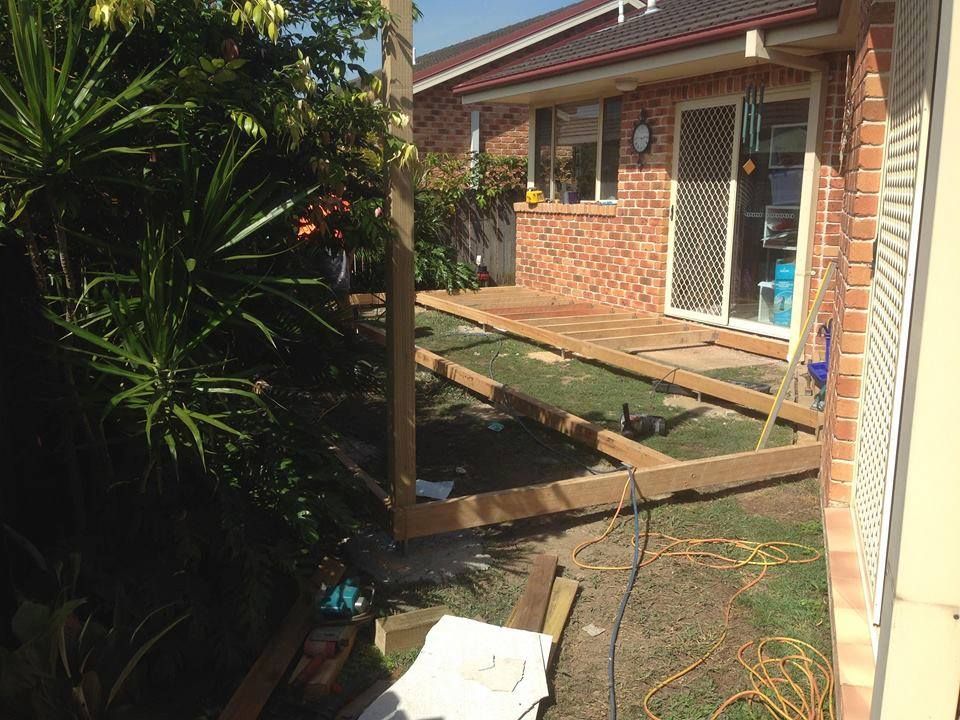 A Wooden Deck is Being Built in Front of a Brick House — Mark Cannon Carpentry & Maintenance in Moonee Beach, NSW