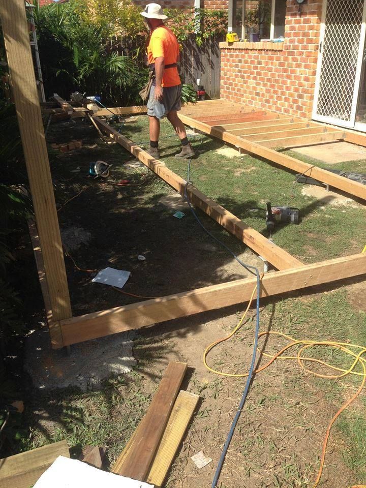 A Man is Working on a Wooden Deck in a Backyard — Mark Cannon Carpentry & Maintenance in Moonee Beach, NSW