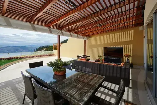 Outdoor patio with wooden pergola, dining table, and lounge area overlooking scenic view.— Mark Cannon Carpentry & Maintenance in Moonee Beach, NSW