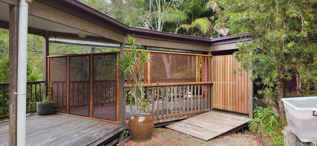 A Wooden Deck With a Fence and a Potted Plant in Front of a House — Mark Cannon Carpentry & Maintenance in Moonee Beach, NSW