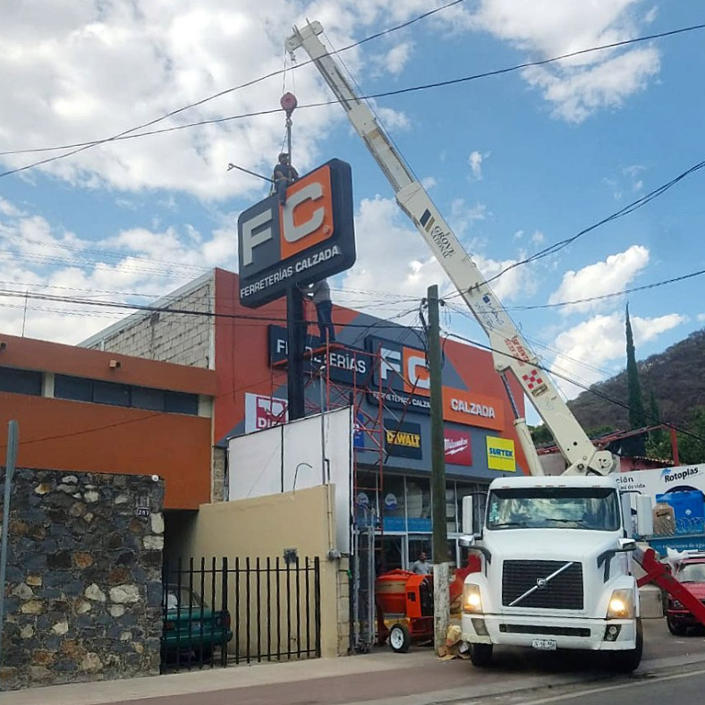 Grúa Montando Anuncios de ferretería calzada