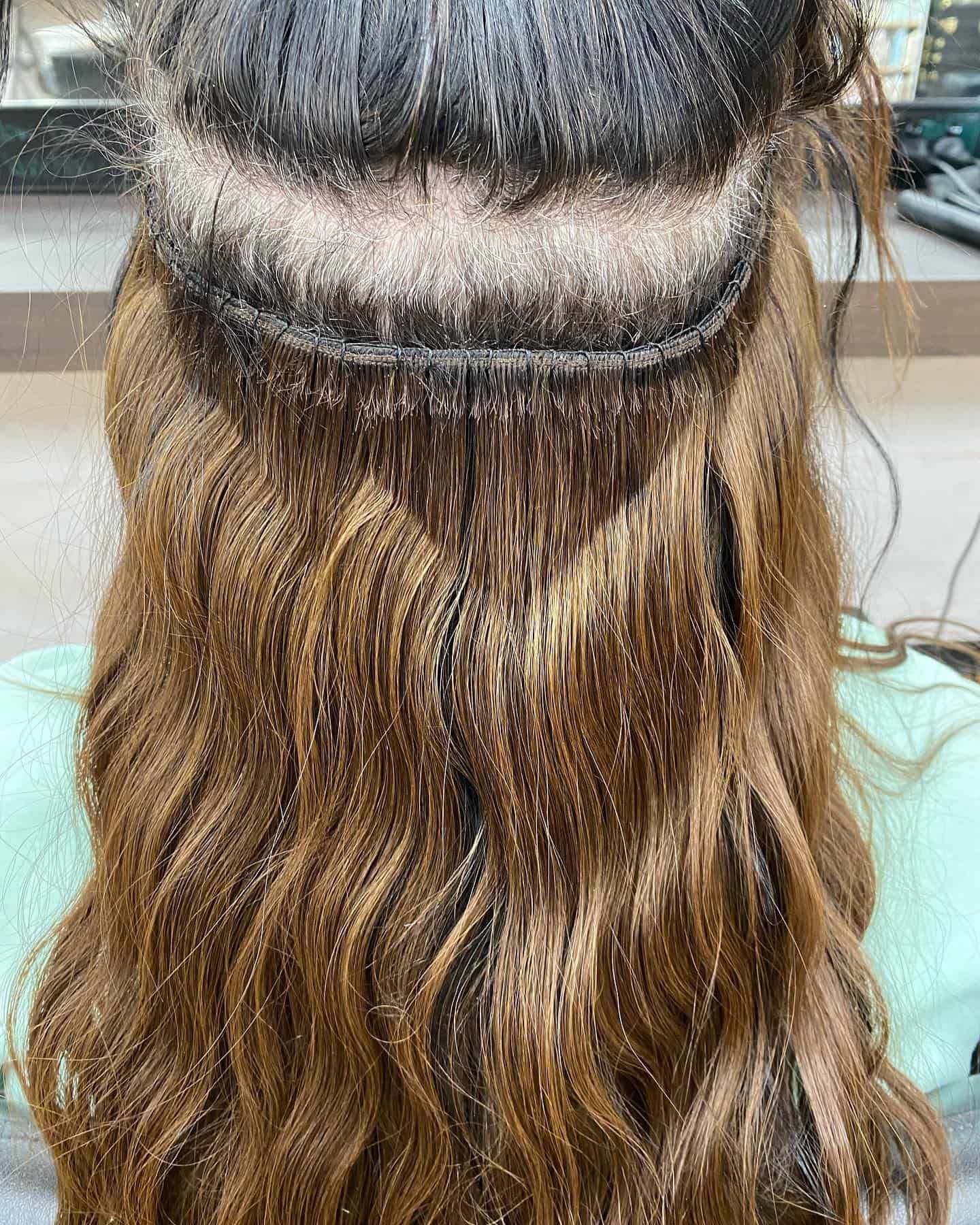 Woman's Back With Brown Curly Hair and Visible Hair Weft Extensions at the Crown — Lavish Hair in Shepparton, VIC