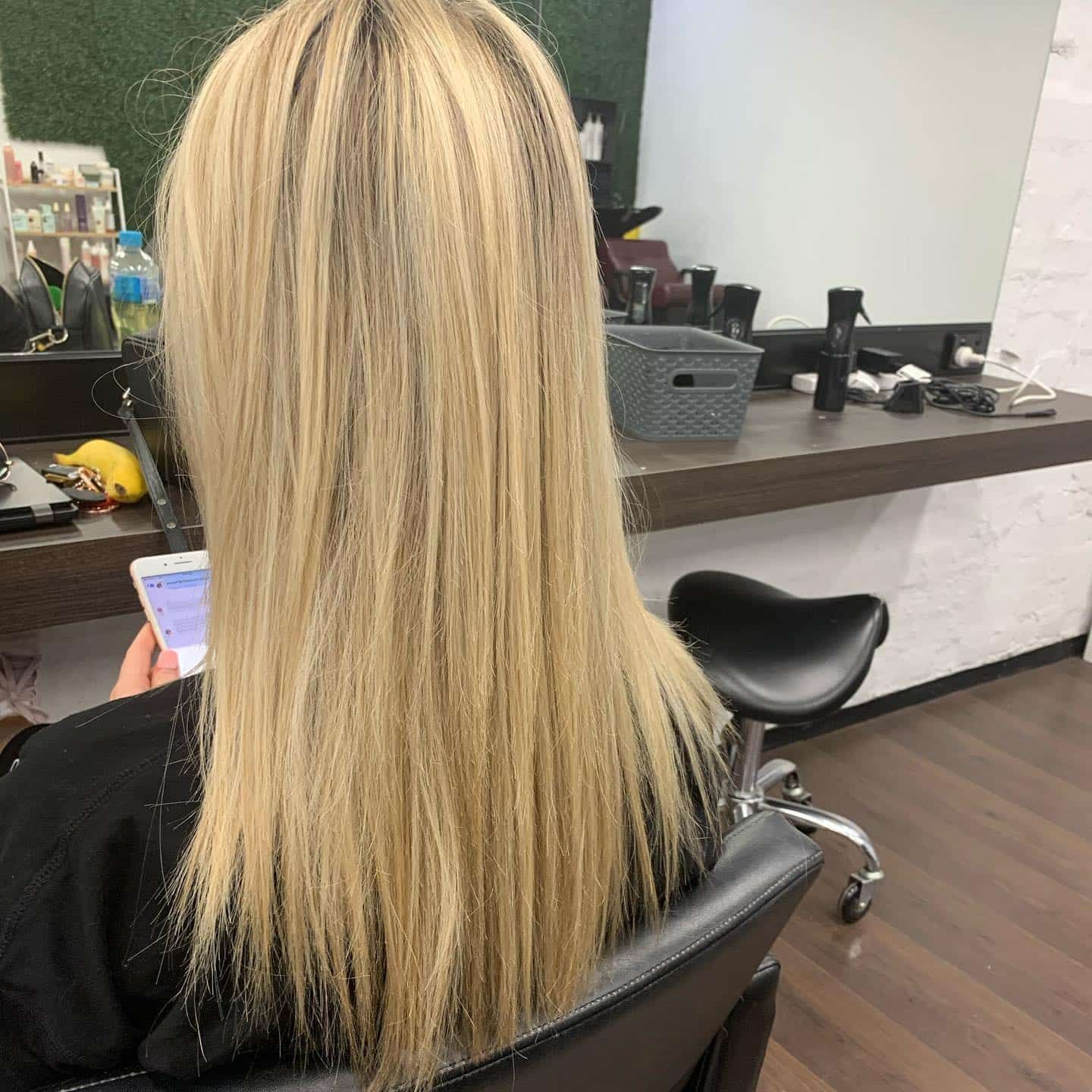 Woman in Salon, Blonde Hair, Looking at Phone — Lavish Hair in Shepparton, VIC