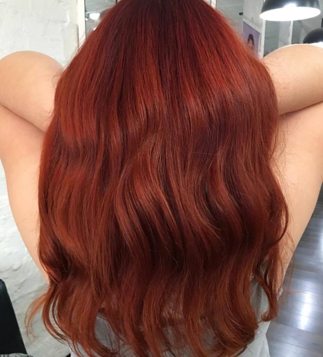 Woman With Long, Wavy, Vibrant Red Hair, Hands Behind Head, Indoors — Lavish Hair in Shepparton, VIC