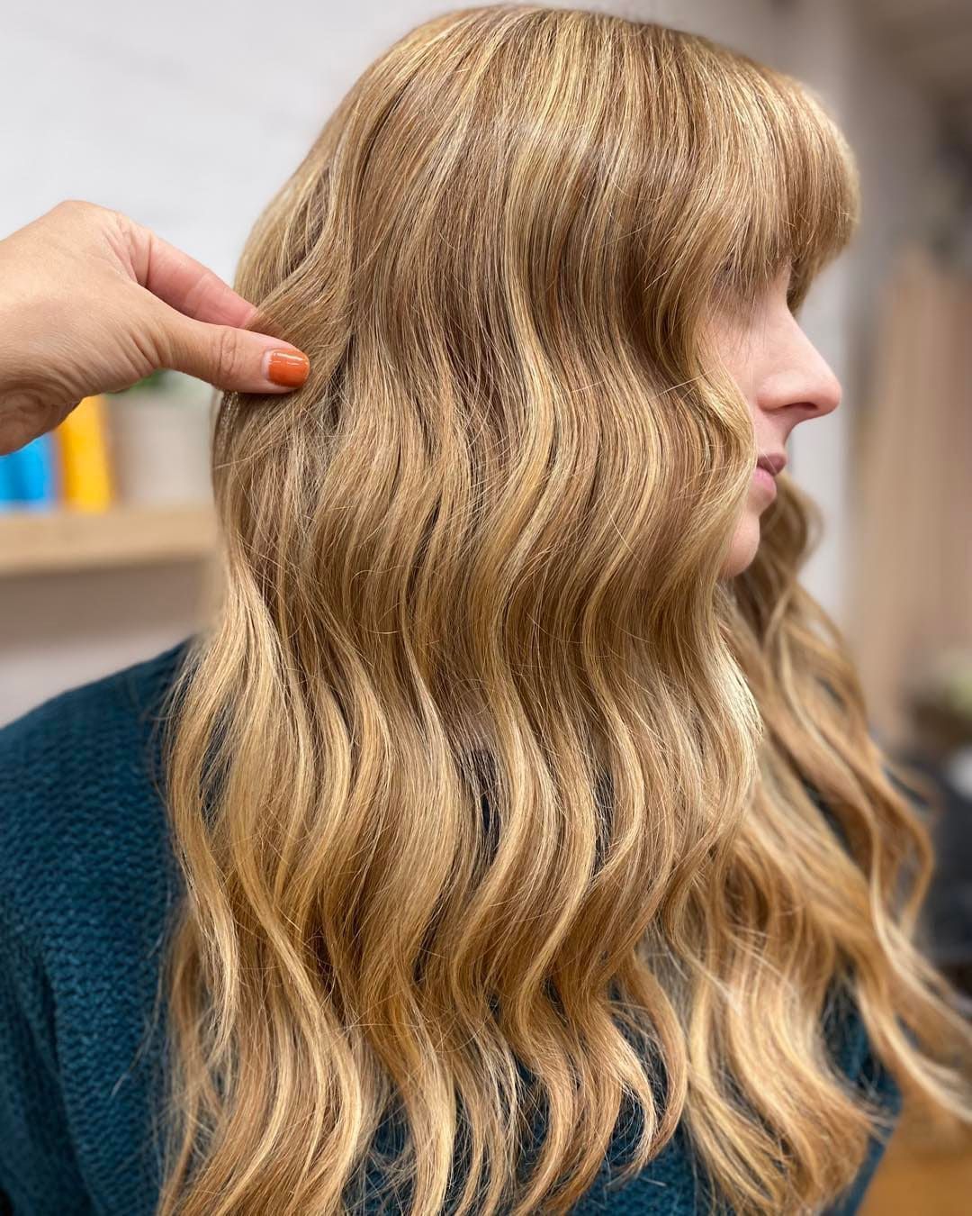 Woman With Wavy Blonde Hair, Bangs, and Highlights, Hand Touching Hair — Lavish Hair in Shepparton, VIC