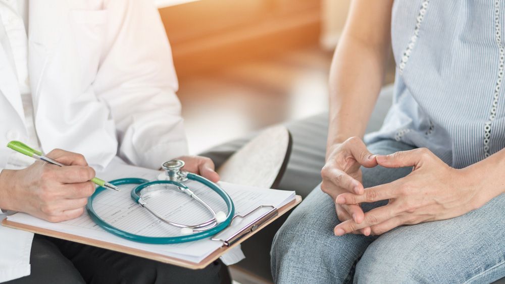 A Doctor Is Talking To A Patient While Holding A Clipboard And A Stethoscope — Wegner Therapies In Pialba, QLD