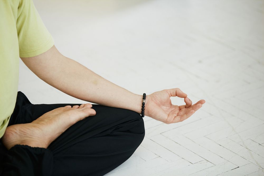 A Person Is Sitting On The Floor In A Lotus Position With Their Hands In A Circle — Wegner Therapies In Pialba, QLD