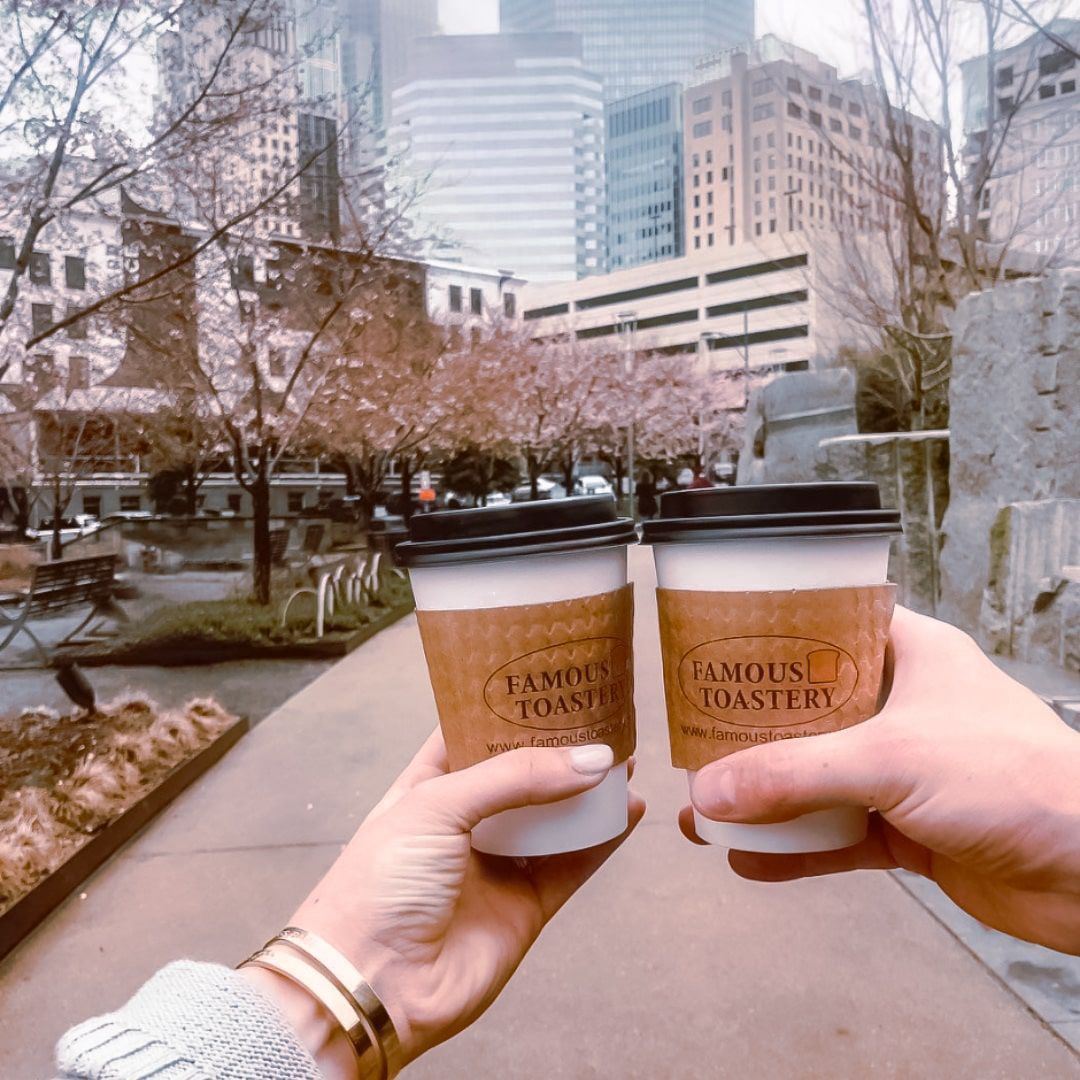 A person is holding two cups of famous roastery coffee