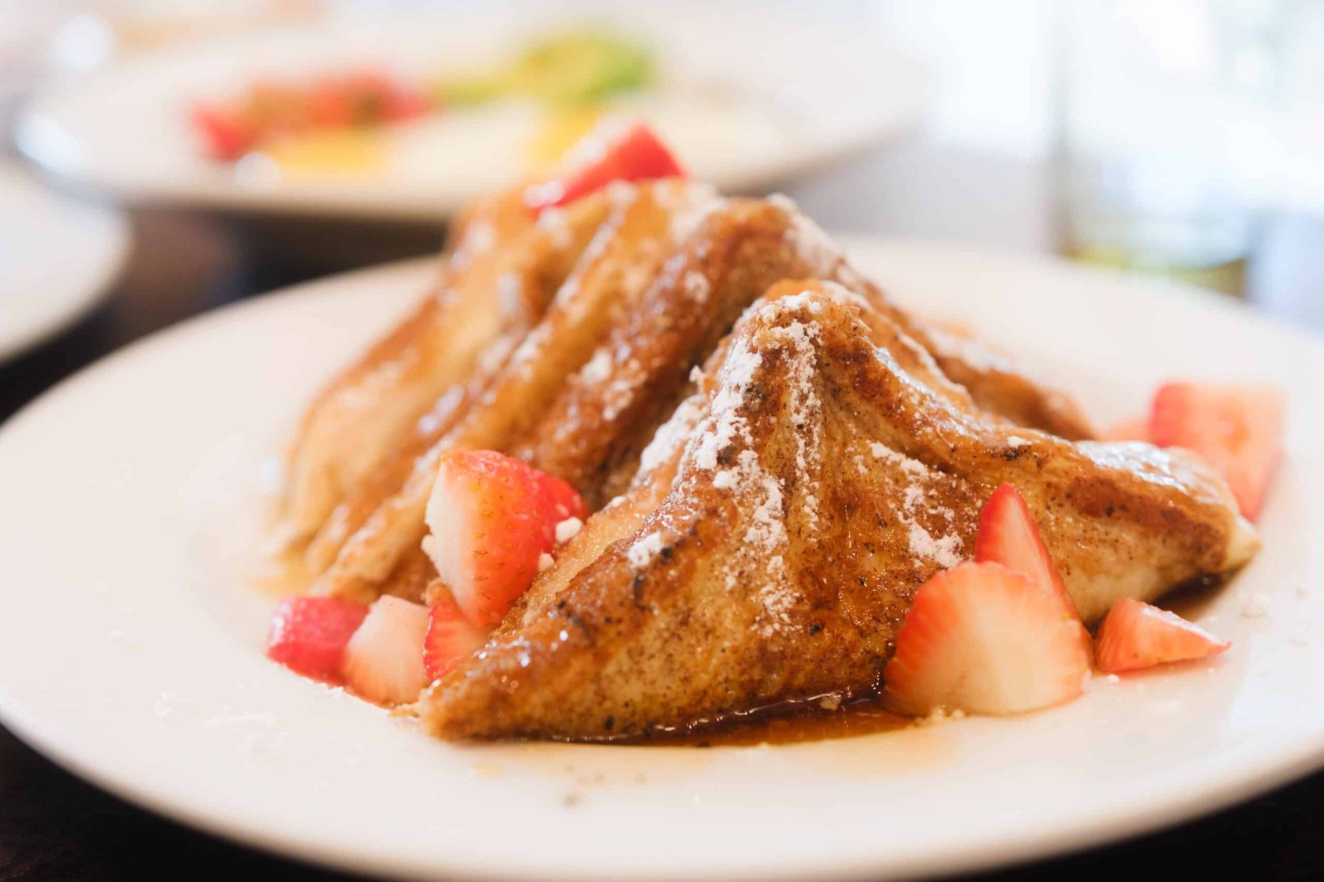 A white plate topped with french toast and strawberries.