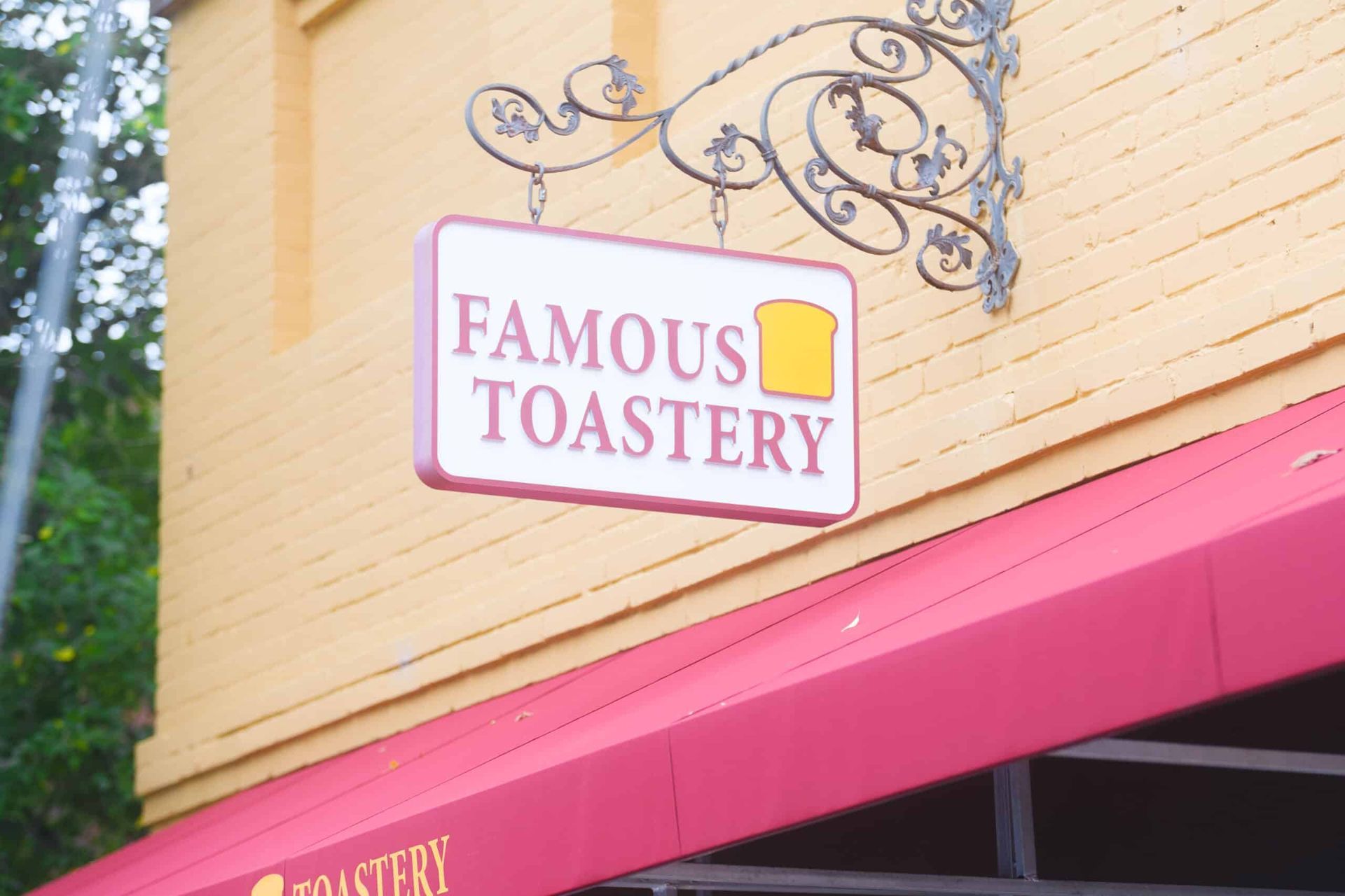 A sign for famous toastery hangs from the side of a building