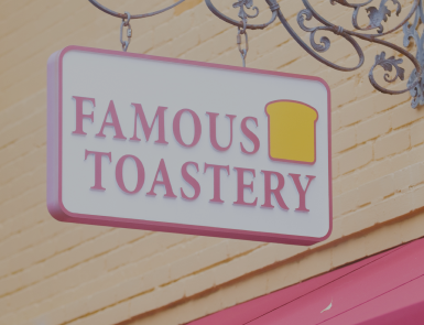 A sign for famous toastery hangs from the side of a building