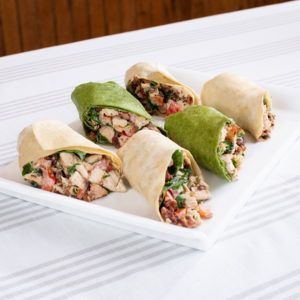 A white plate topped with a variety of wraps on a table