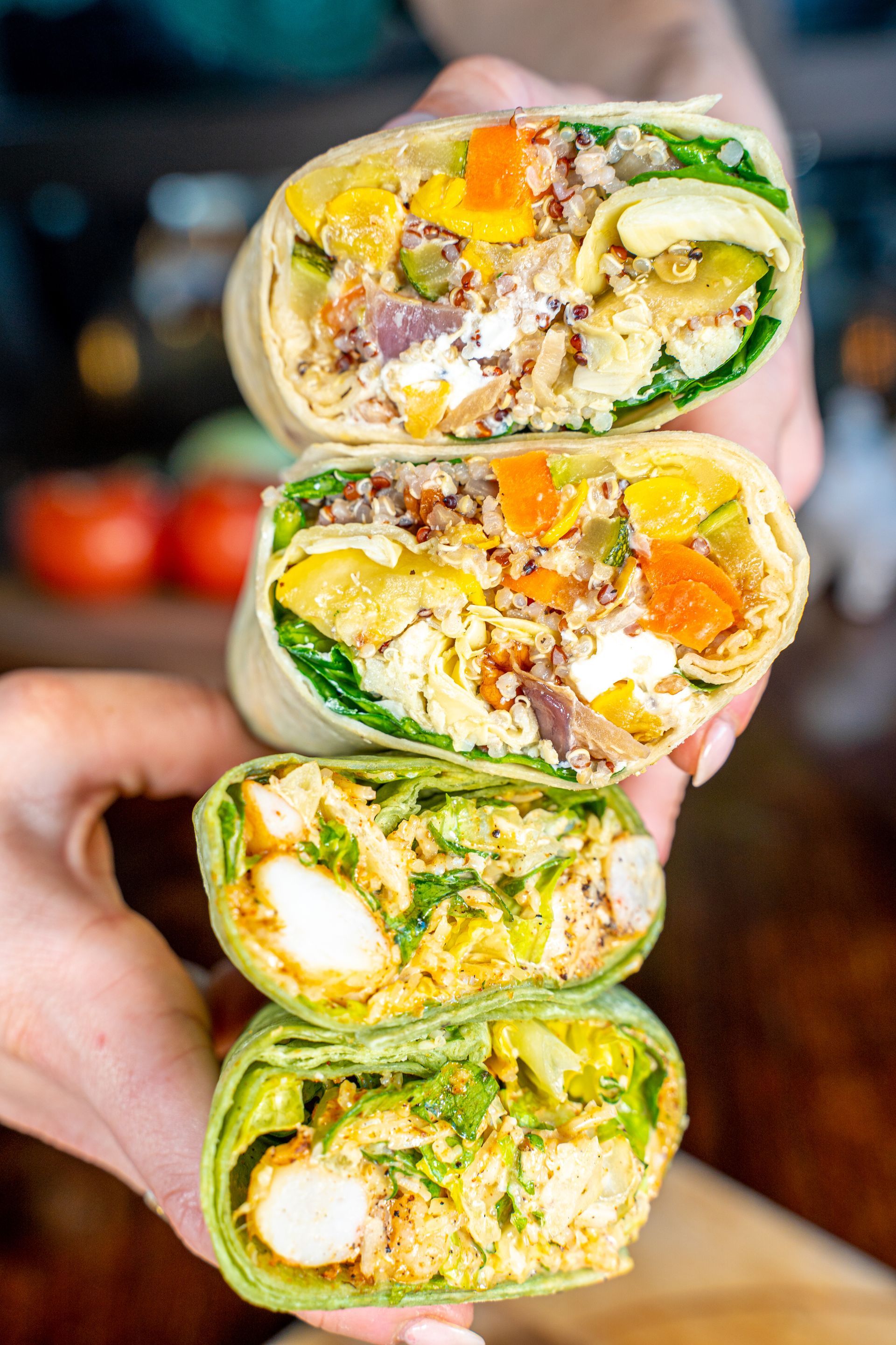 A person is holding three burritos stacked on top of each other.