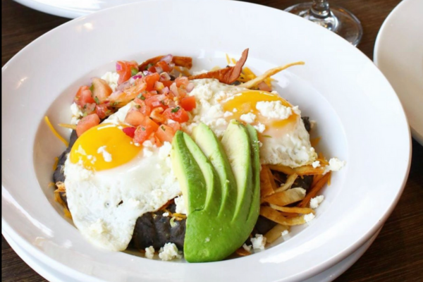 A bowl of food with eggs and avocado on a table