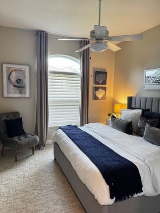 A beige bedroom featuring window blinds and drapes