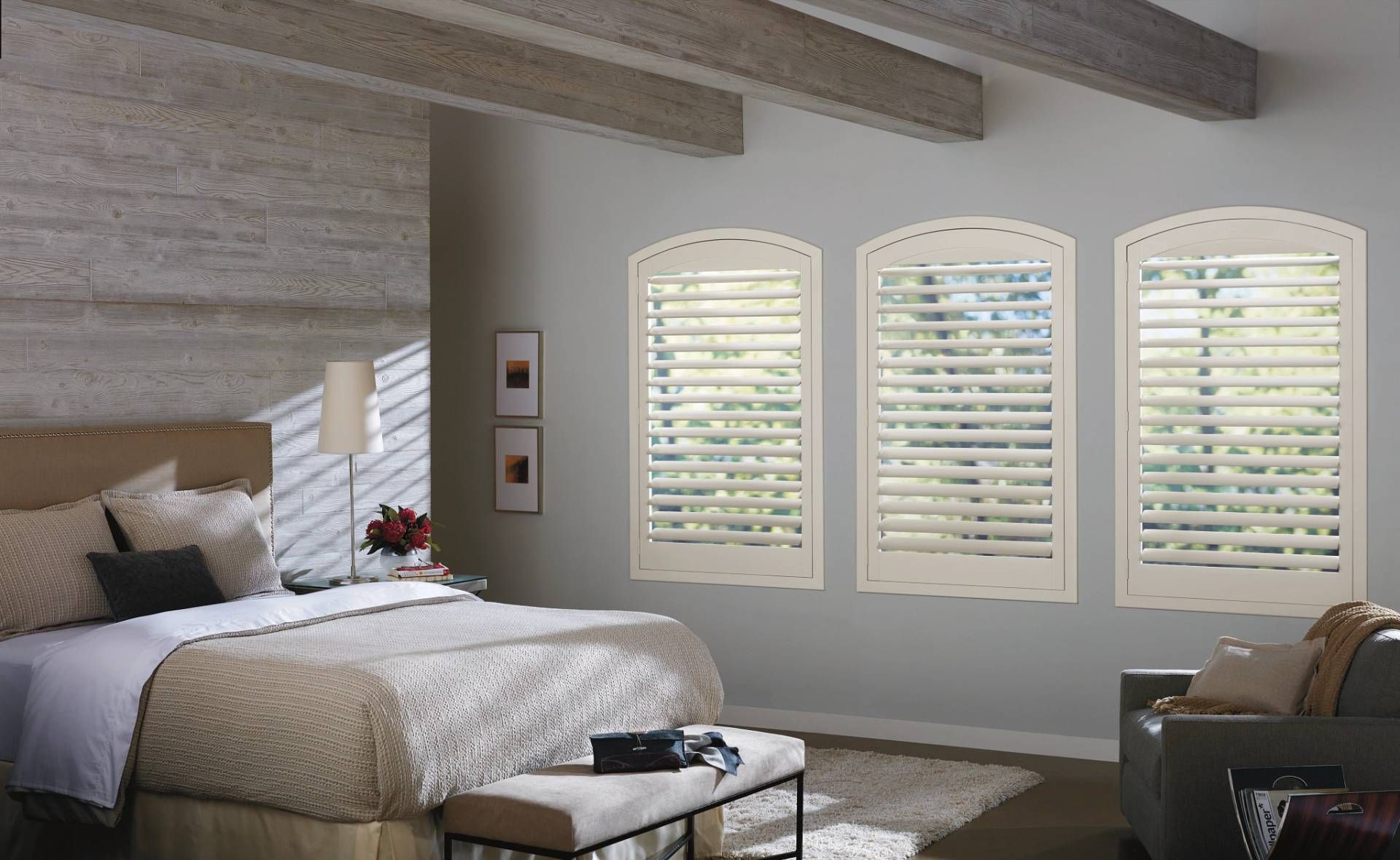 A primary bedroom with a contemporary style and Hunter Douglas shutters on three windows