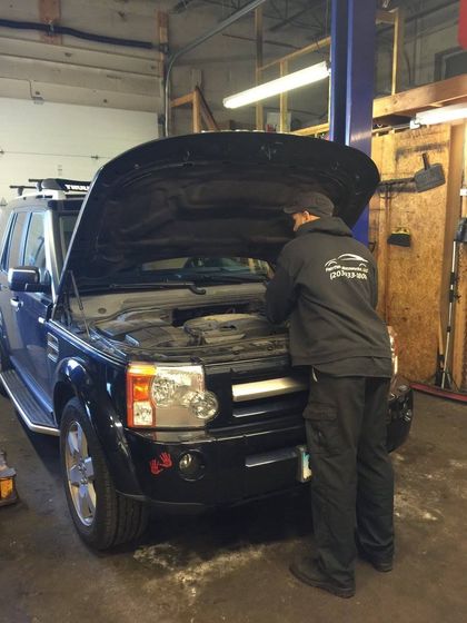Mechanic working on a black SUV with the hood open | Fairfield Motoworks LLC