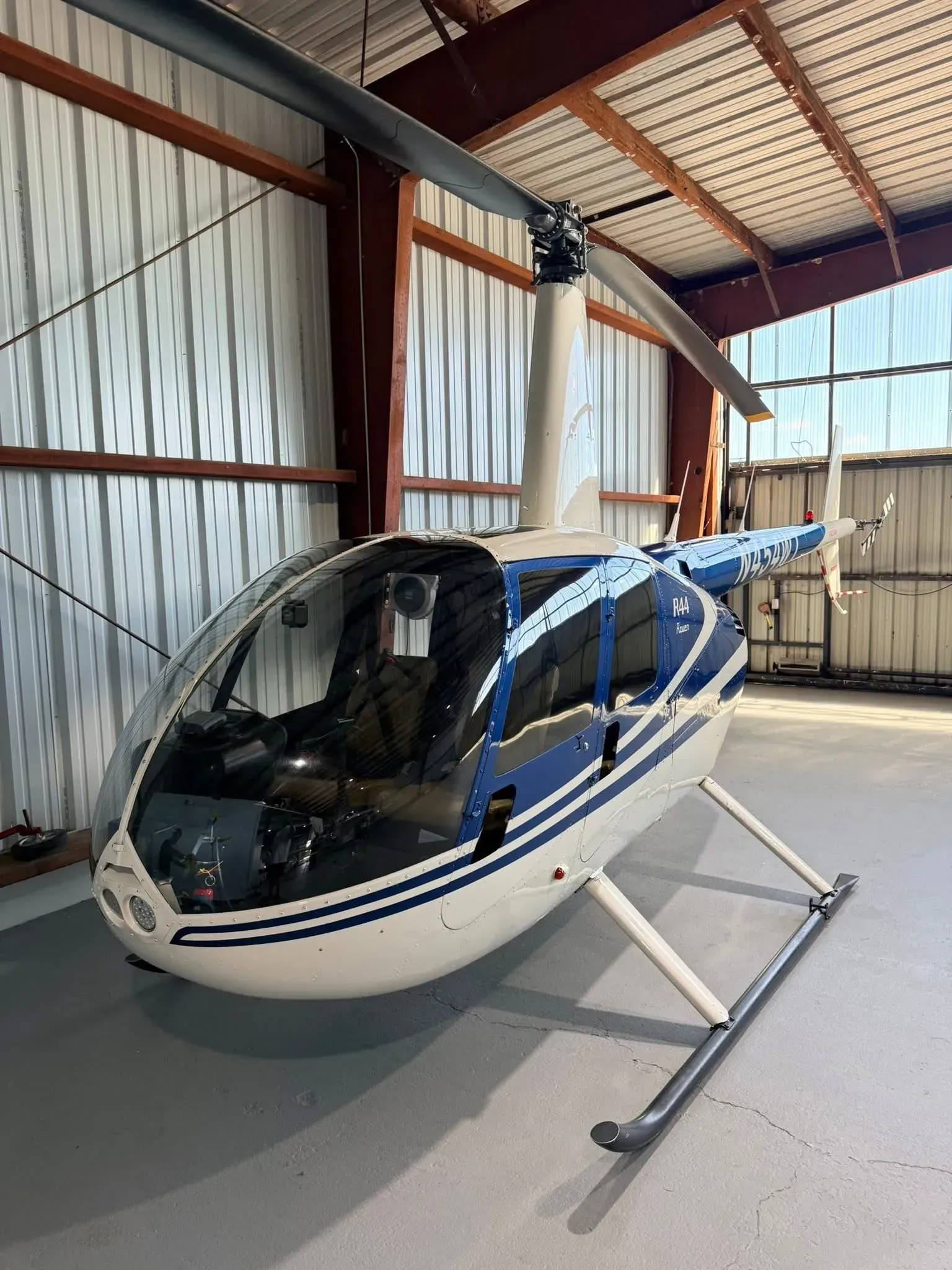 Blue and white helicopter parked inside a hangar.