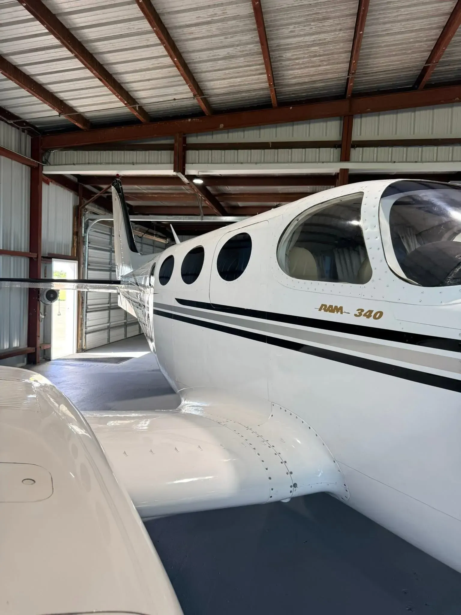White and gray airplane inside a hangar; the plane has black-rimmed windows and a tail fin.