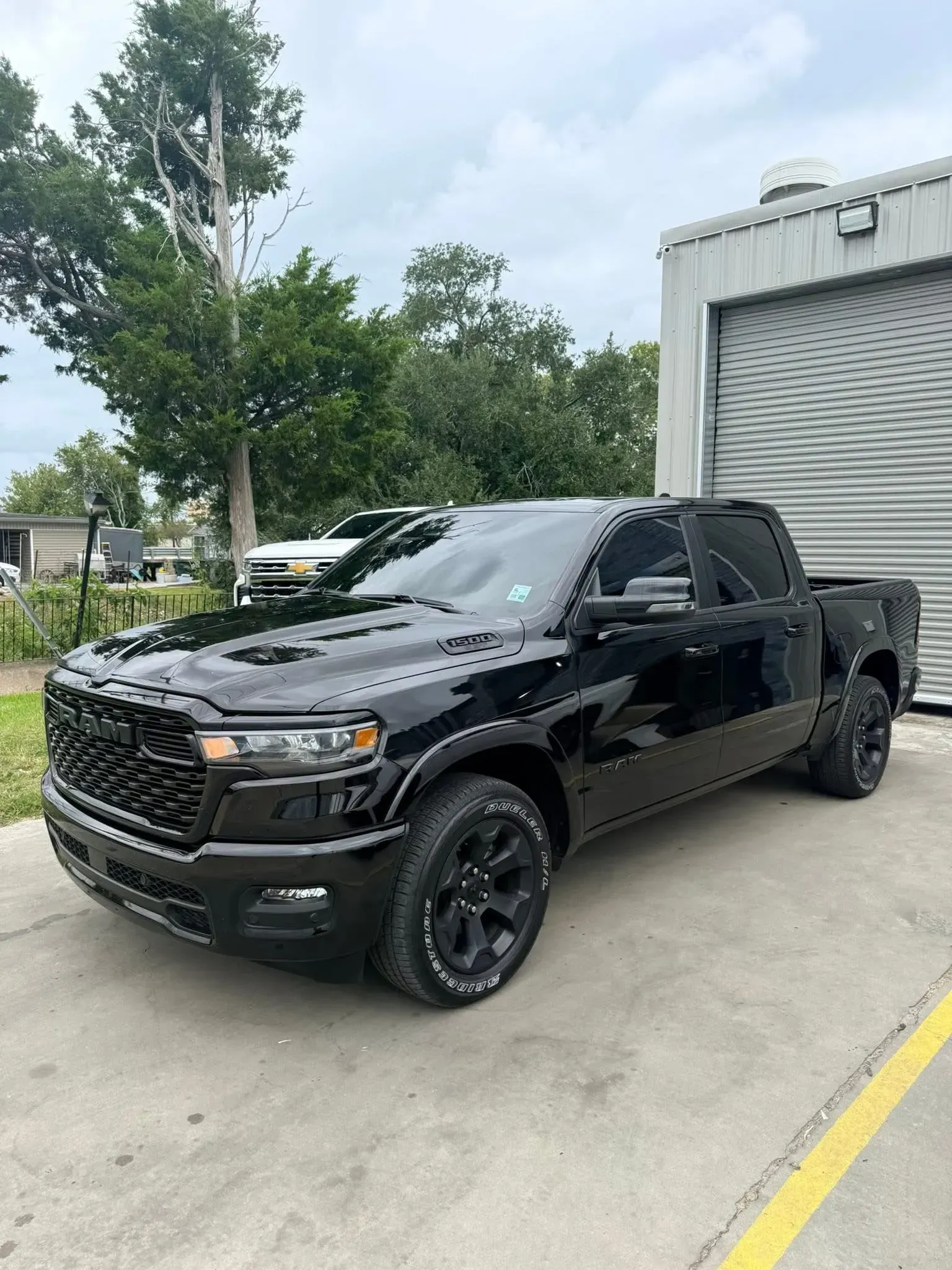 Black Ram pickup truck parked on concrete, next to a building.