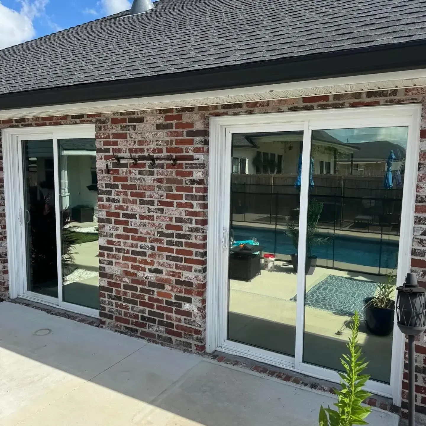 Brick building exterior with two sliding glass doors, pool visible through right door.