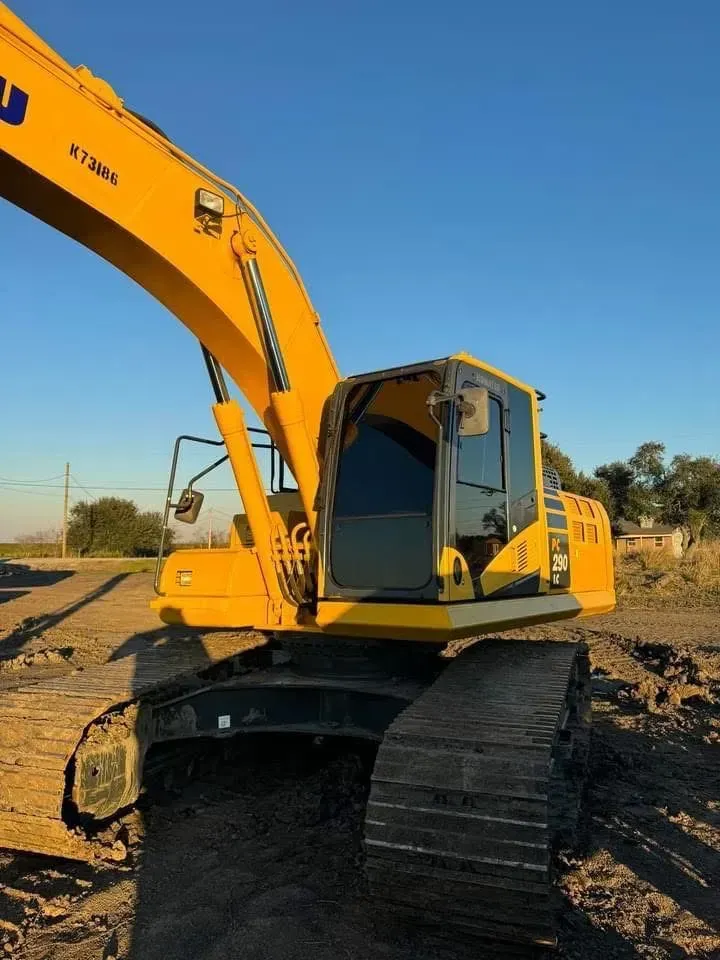 Yellow excavator on a dirt ground under a clear blue sky.