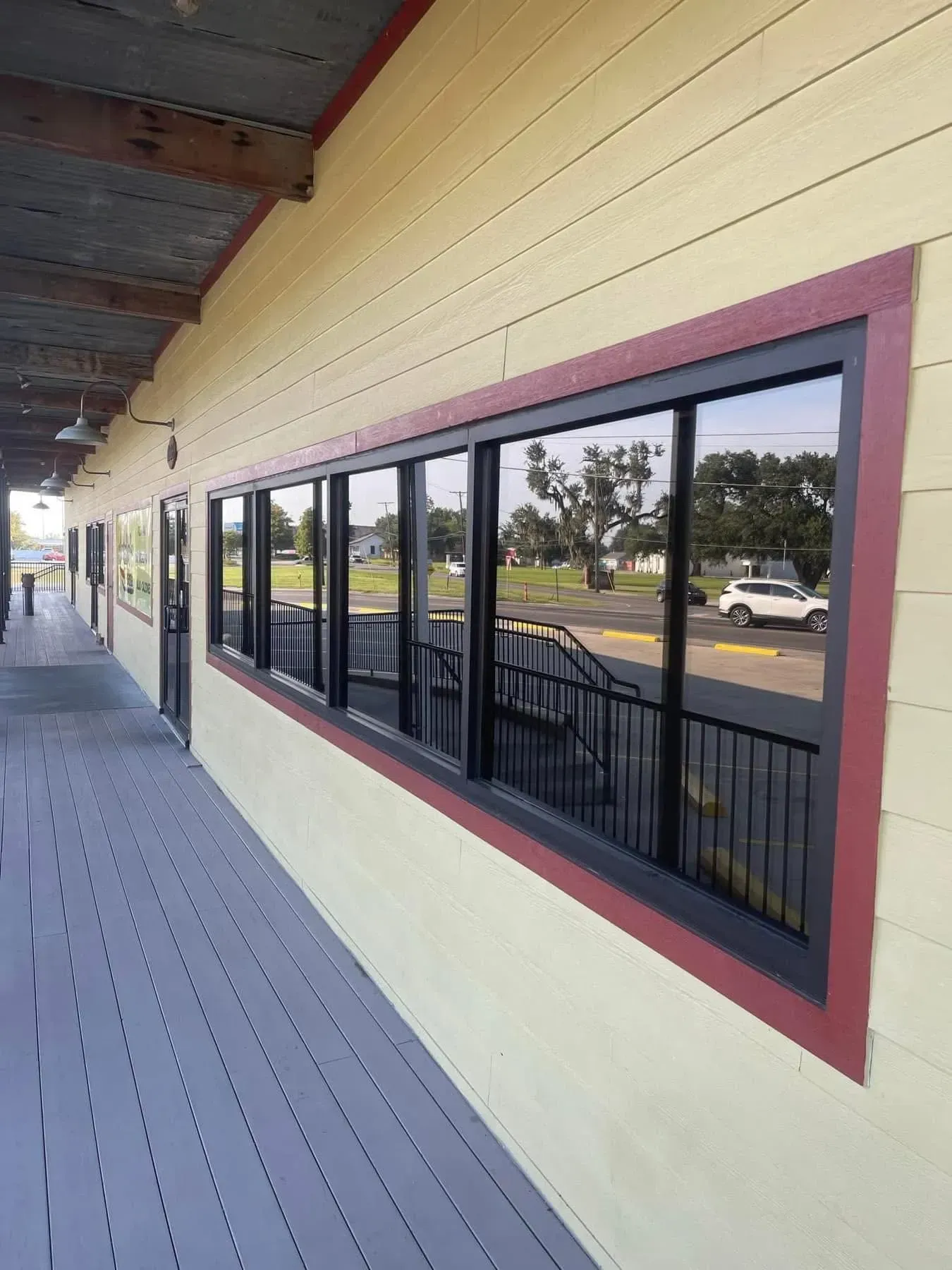 Exterior of a building with a row of windows, black frames, red trim, and a gray walkway.