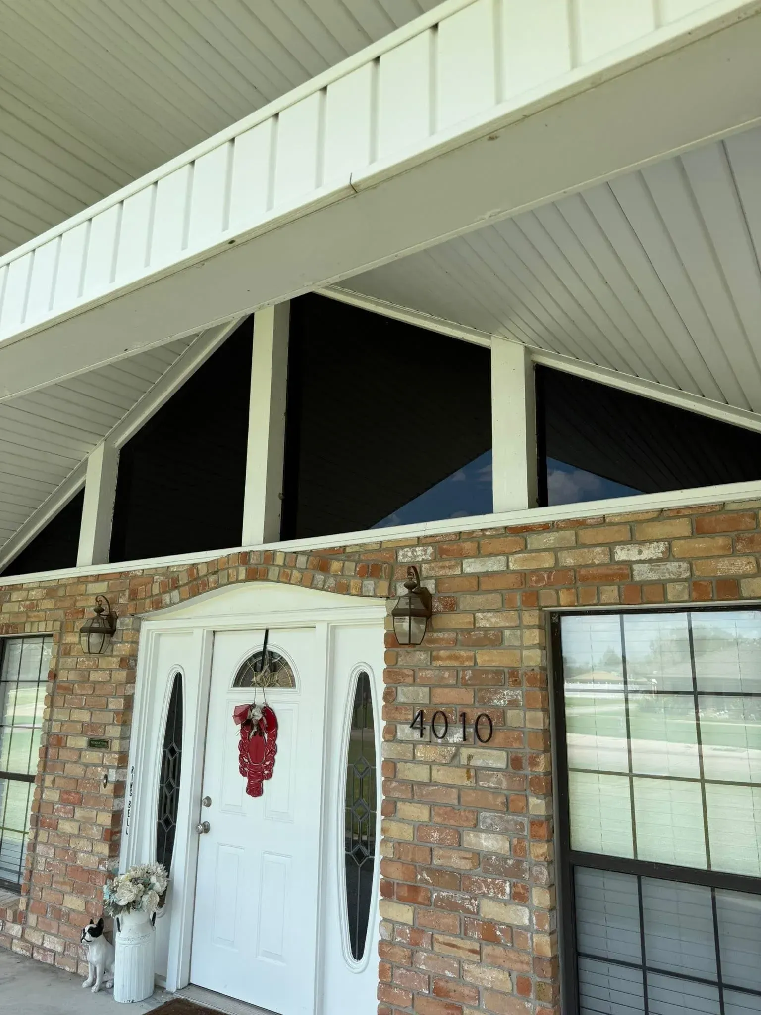 Brick home exterior with white door, sidelights, address 