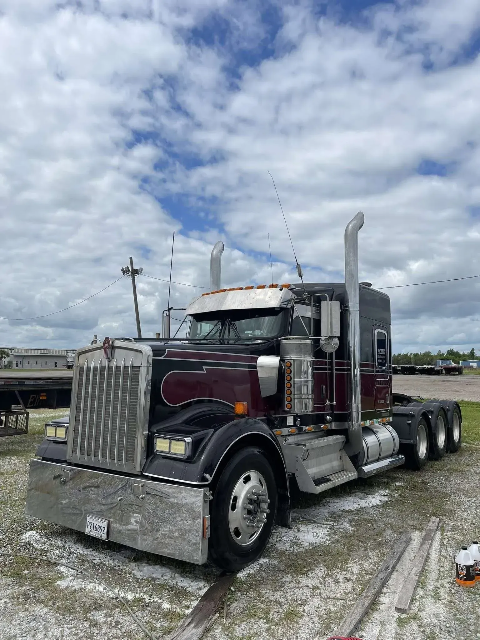 Dark burgundy semi-truck parked outdoors on a cloudy day; chrome accents visible.