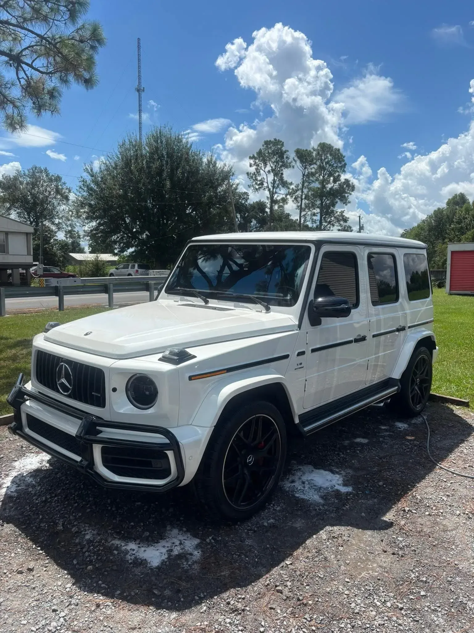 White Mercedes-Benz G-Class SUV parked outdoors on a sunny day with black wheels and trim.