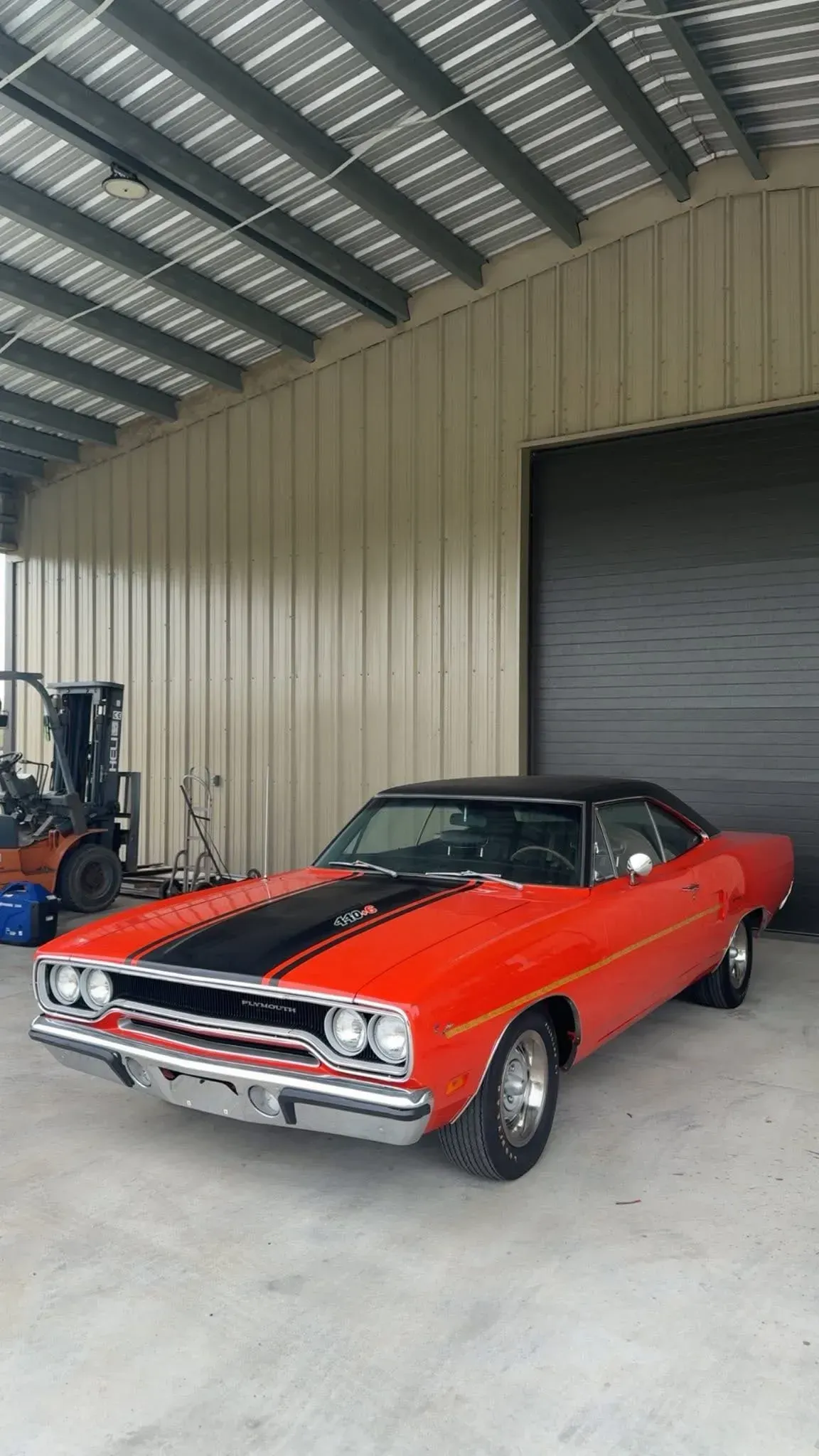 Red and black classic car parked inside a garage.