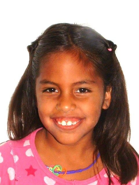 Chica con cabello castaño y camisa rosa sonriendo.