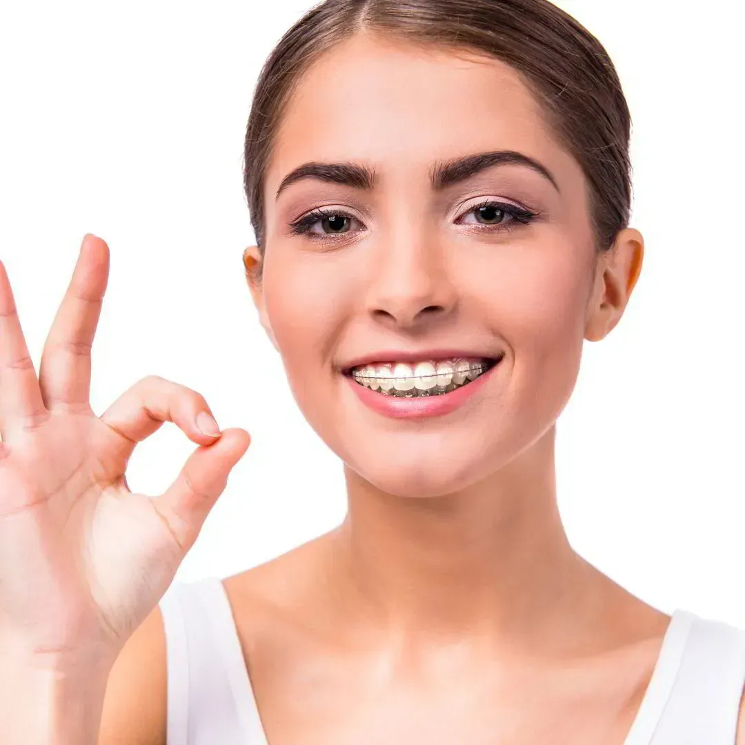 Una mujer con aparatos ortopédicos sonrÃe y hace un gesto con la mano diciendo