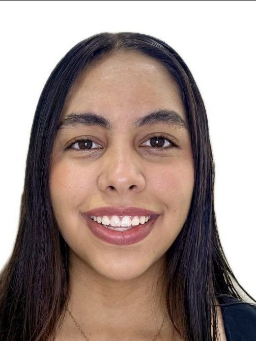 Una mujer con cabello largo y oscuro sonríe, con dientes blancos visibles, sobre un fondo blanco.