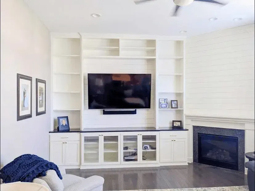A living room with a fireplace and a flat screen tv on the wall.