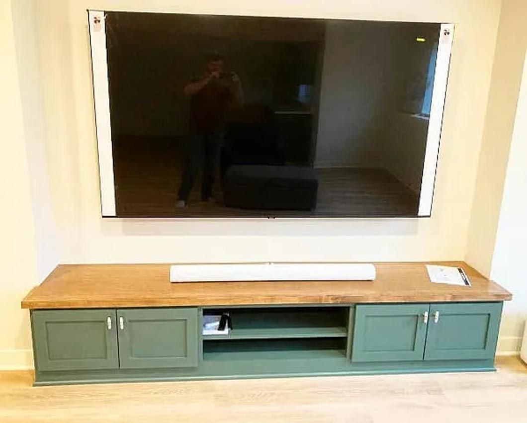 A large flat screen tv is mounted on a wall above a wooden entertainment center.