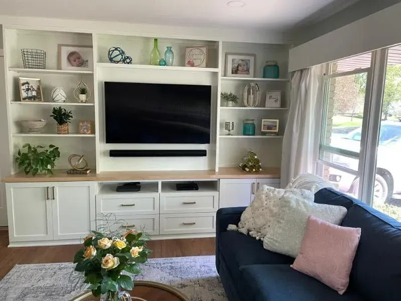 A living room with a couch , television , and shelves.