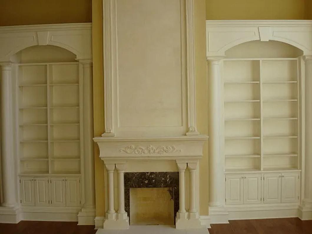 There is a fireplace in the middle of the room surrounded by shelves.
