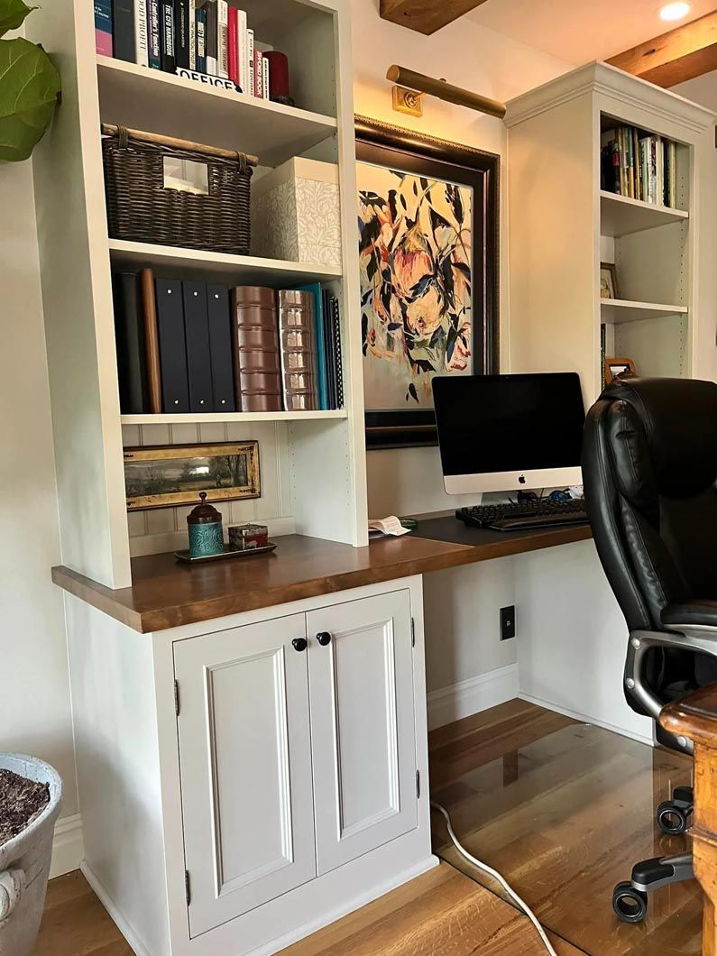 A home office with a desk , chair , computer and shelves.